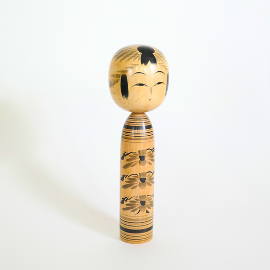 Profil d'une kokeshi japonaise de style Tôgatta aux motifs noirs et gris