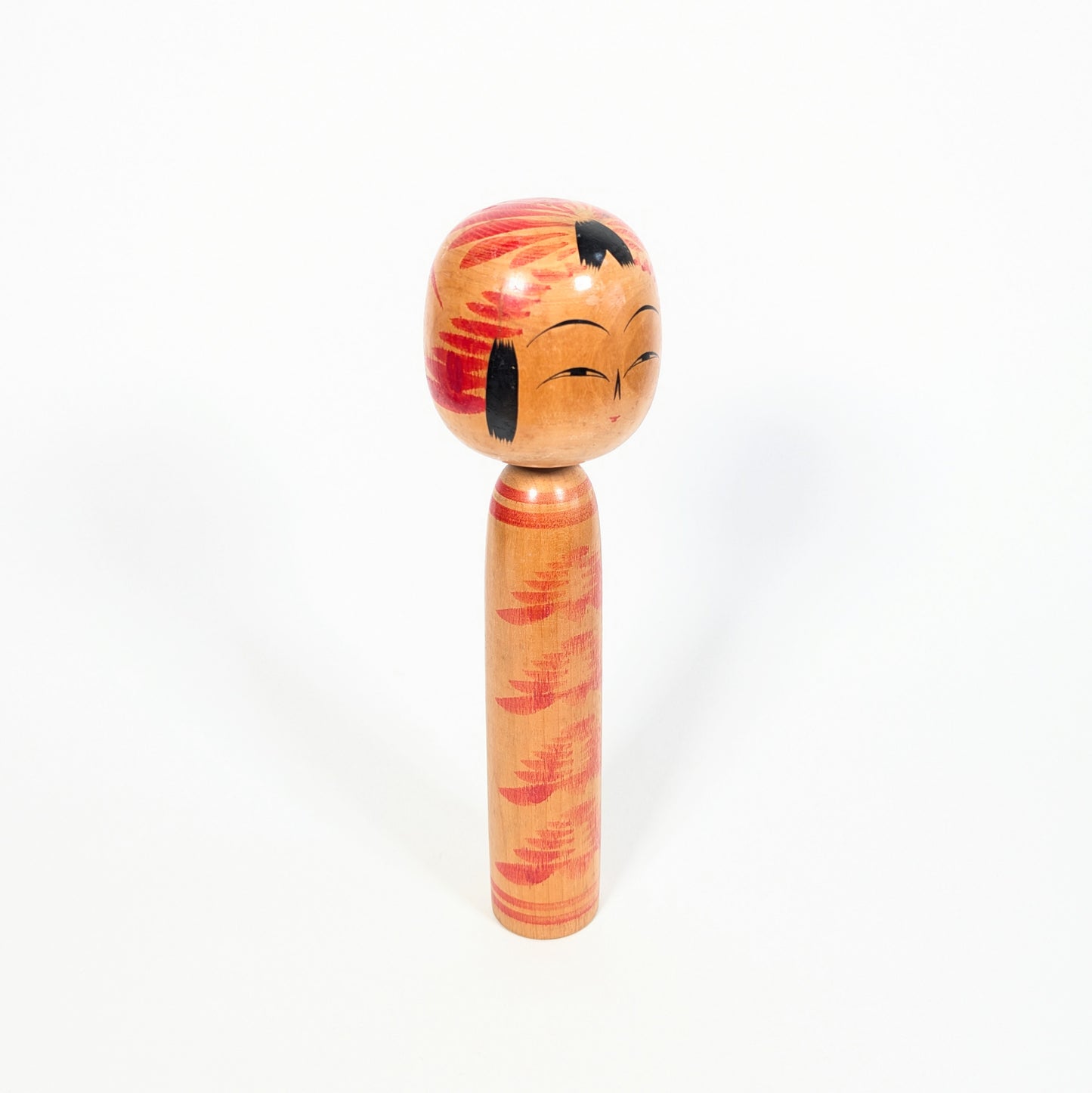 Profil d’une dentō kokeshi Togatta, tête décorée d’un motif tegara traditionnel, mèches noires et corps élancé à motif kasanegiku.