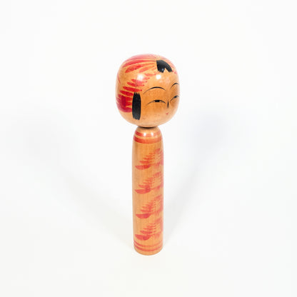 Profil d’une dentō kokeshi Togatta, tête décorée d’un motif tegara traditionnel, mèches noires et corps élancé à motif kasanegiku.