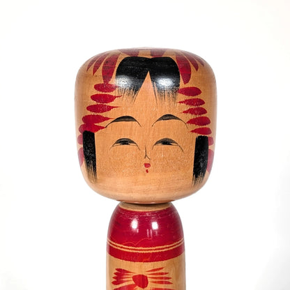 Visage peint à la main d’une kokeshi Togatta traditionnelle, expression douce et stylisée