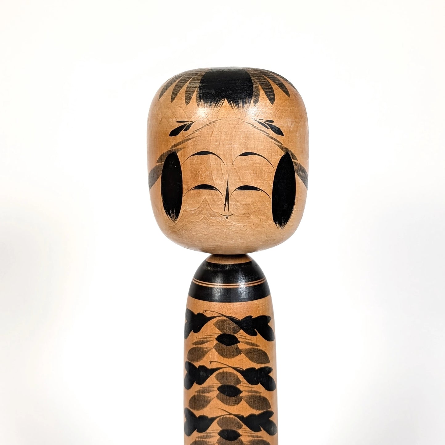 Détail du visage souriant d’une kokeshi Togatta japonaise, sculpture traditionnelle en bois par Sato Shigekazu, style classique Miyagi