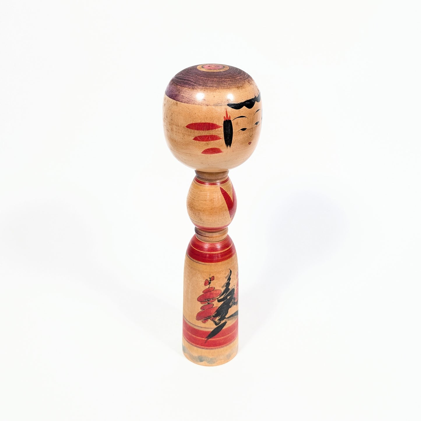 Kokeshi traditionnelle de Miyagi vue de trois quarts, poupée japonaise en bois tourné ornée de fleurs de prunier
