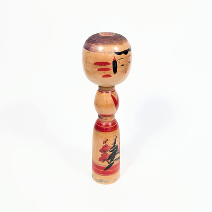 Kokeshi traditionnelle de Miyagi vue de trois quarts, poupée japonaise en bois tourné ornée de fleurs de prunier