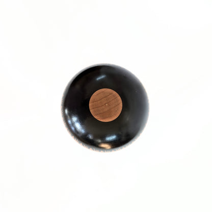 Vue du dessus d'une kokeshi artisanale japonaise Oshin de Mamoru Izu en bois laqué noir