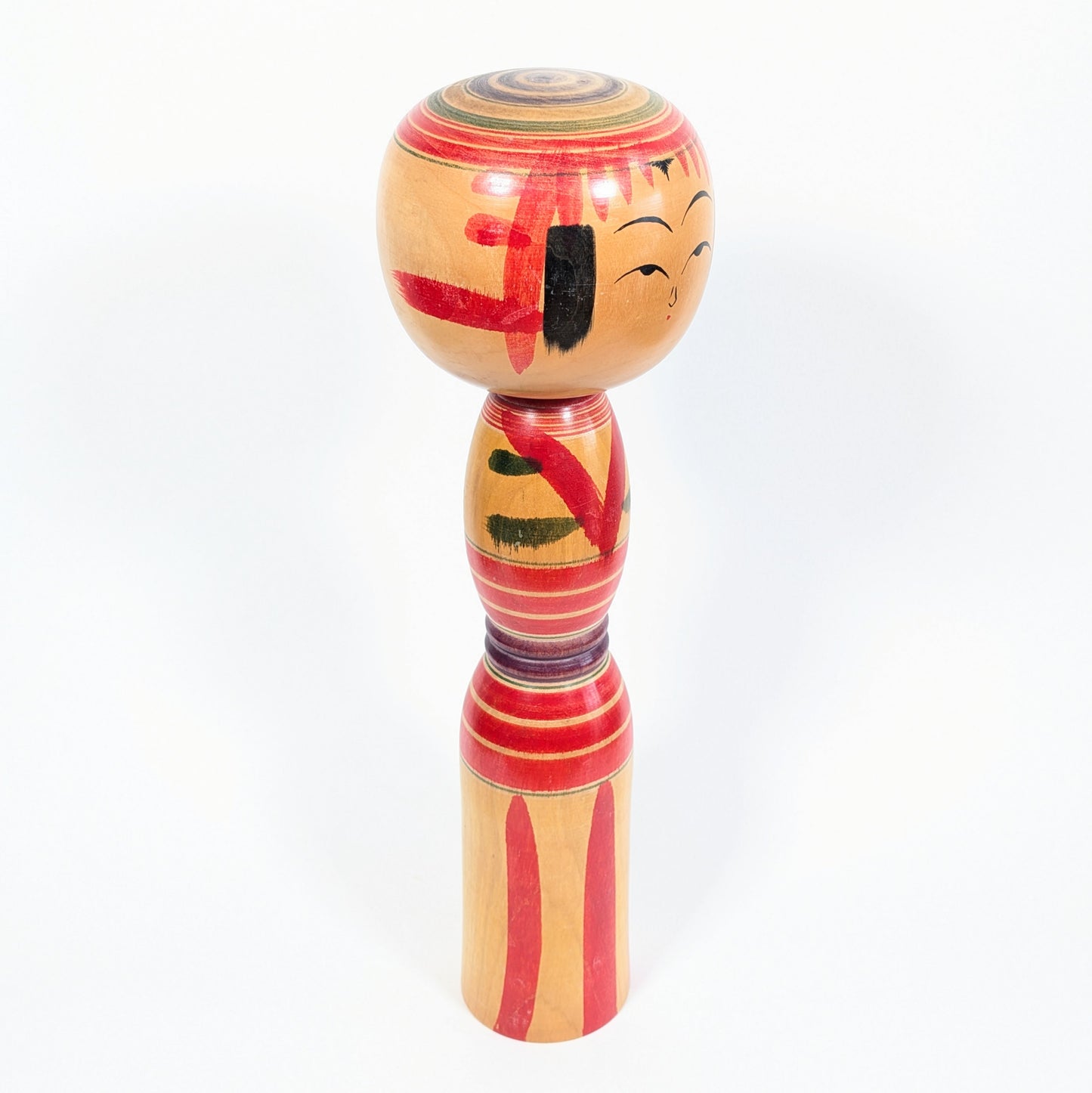 Kokeshi traditionnelle Yajirō signée Niiyama Hisashirō, vue de profil avec frange rouge, mèches noires et motifs peints à la main