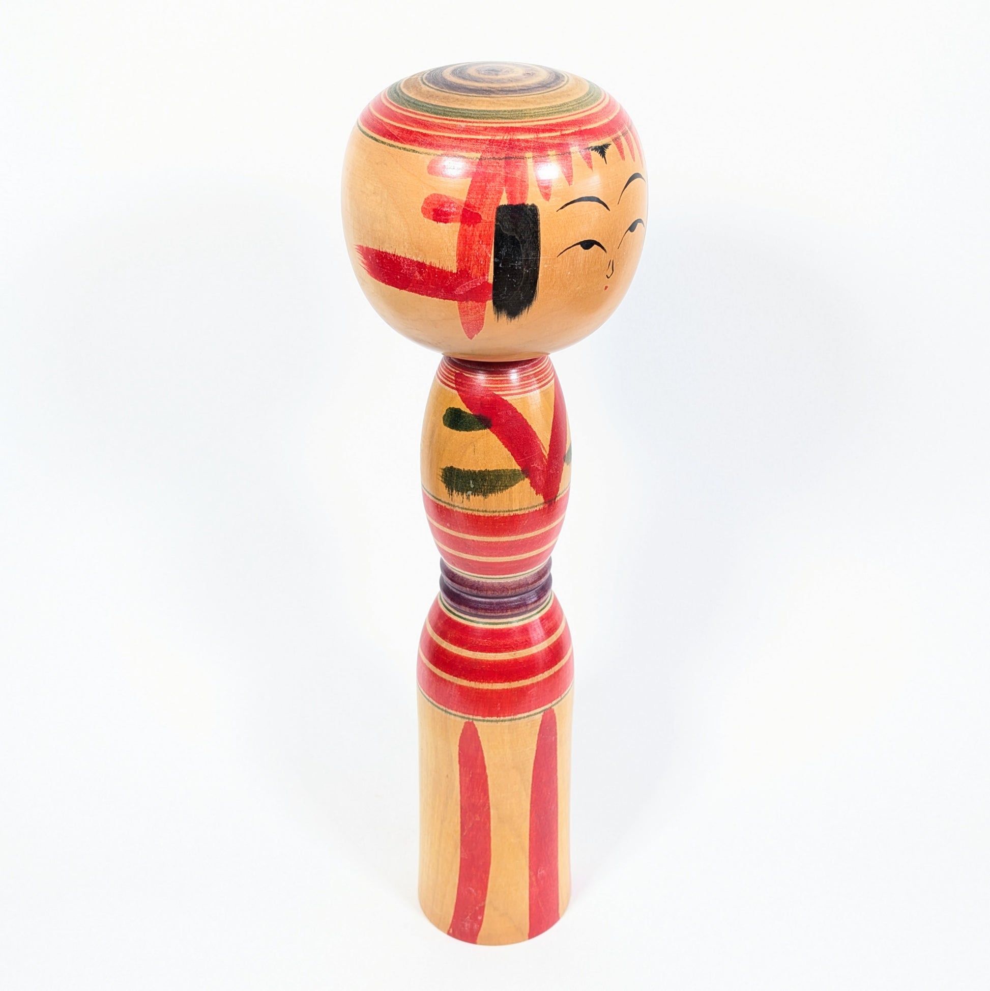 Kokeshi traditionnelle Yajirō signée Niiyama Hisashirō, vue de profil avec frange rouge, mèches noires et motifs peints à la main