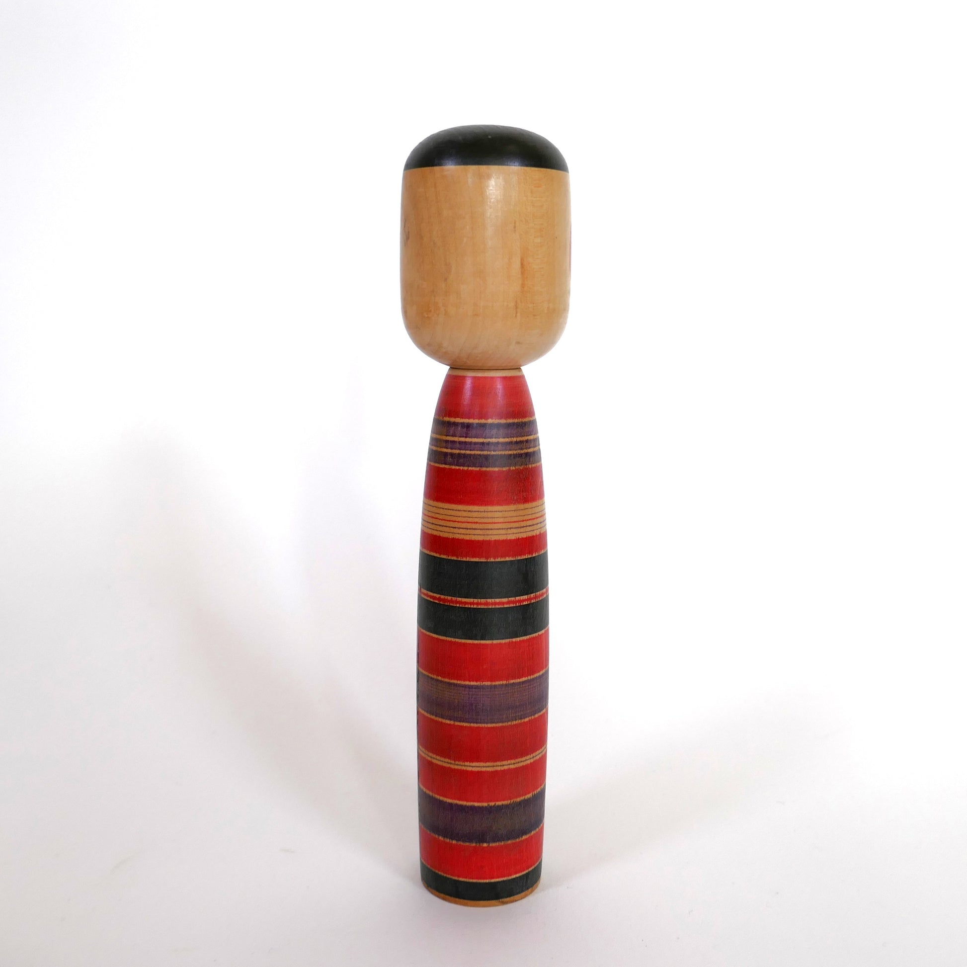 Vue arrière d'une kokeshi japonaise artisanale style Tsuchiyu rouge, violet et noir