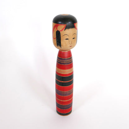 Profil droit d'une kokeshi vintage Tsuchiyu rouge et noir signée Sato Sashima
