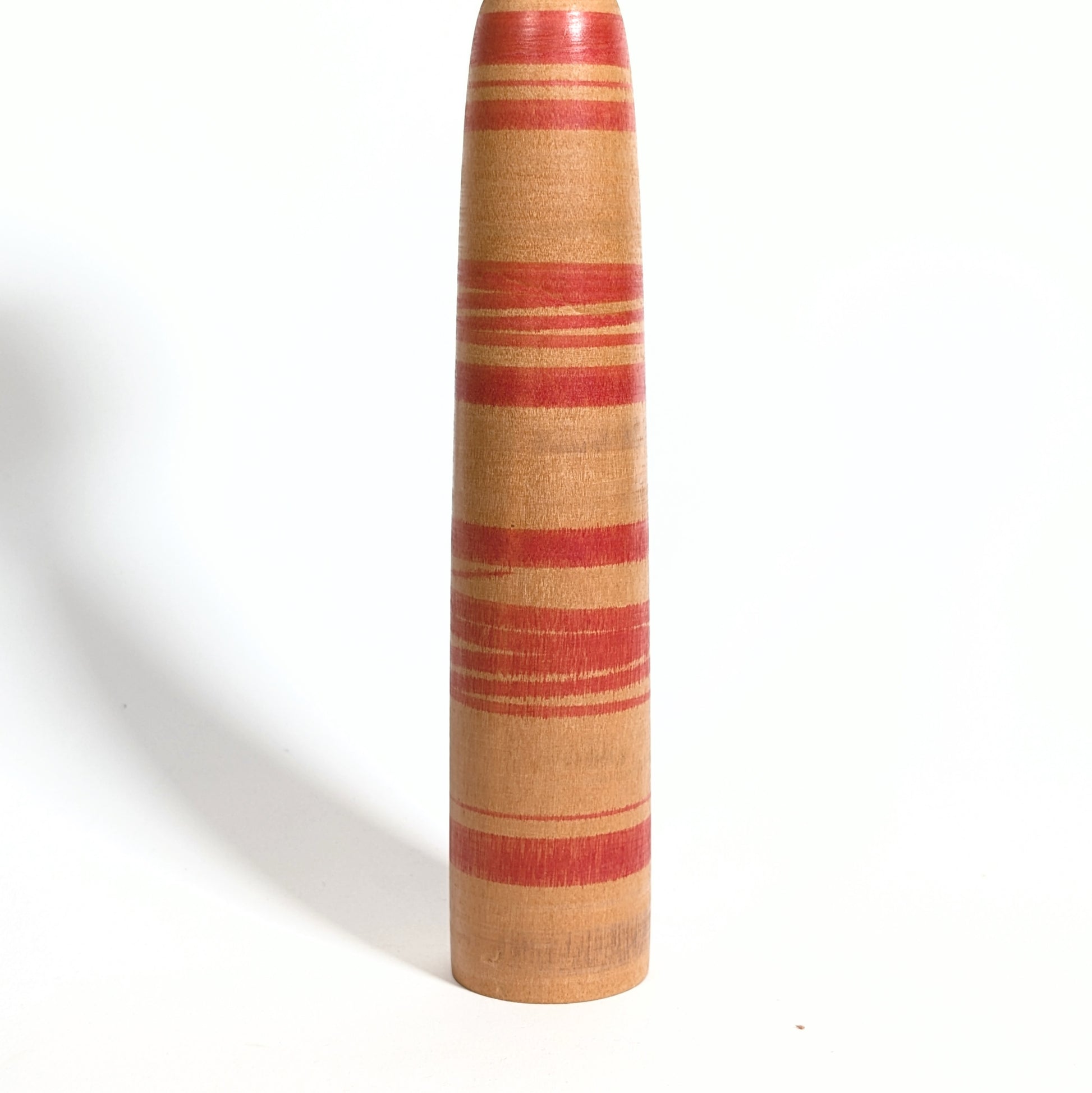 Détail du corps rayé rouge d’une kokeshi Tsuchiyu Watanabe Chuzo en bois massif tourné, artisanat japonais