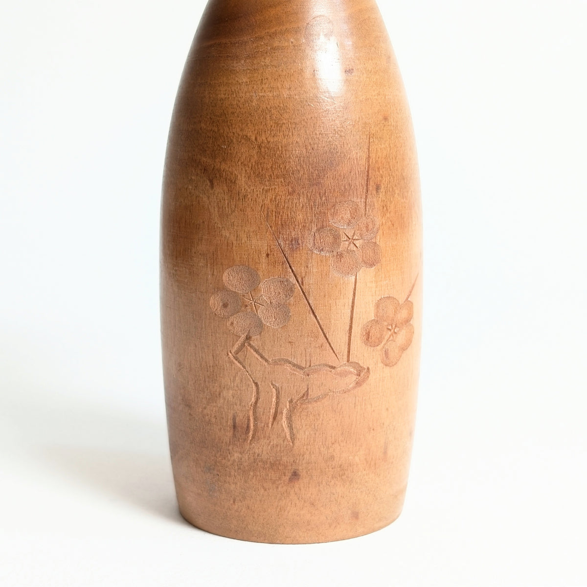 Détail du décor de fleurs de prunier ume gravé sur le corps en bois de la kokeshi japonaise