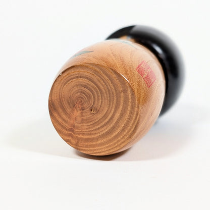 Base en bois naturel d’une kokeshi sosaku Usaburo modèle Haru no uta avec veinage visible et sceau d’artiste rouge