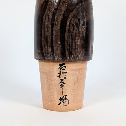 Détail de l'inscription japonaise 石打スキー場, faisant référence à la station de ski d'Ishiuchi dans la préfecture de Niigata, peinte au dos d'une kokeshi Usaburo.