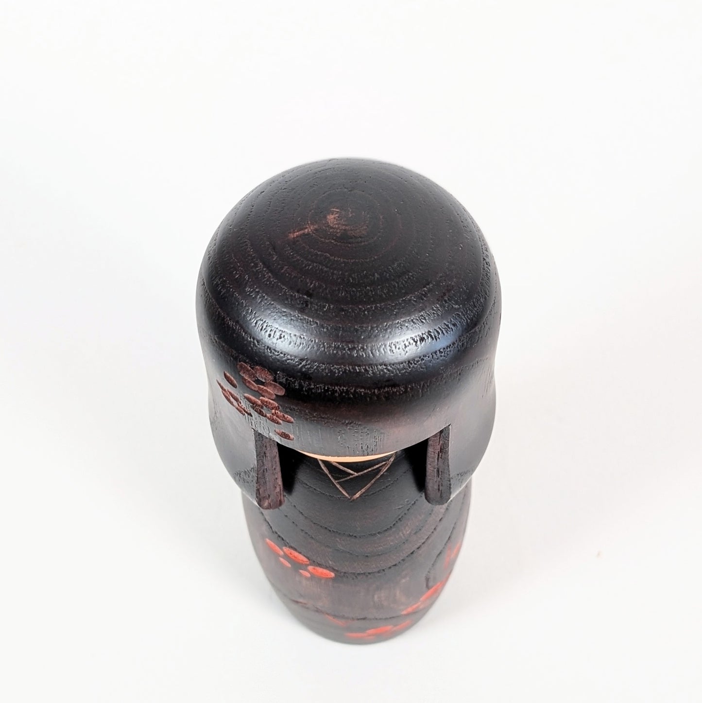 Vue du dessus d’une kokeshi Usaburo avec coiffure okappa en bois foncé