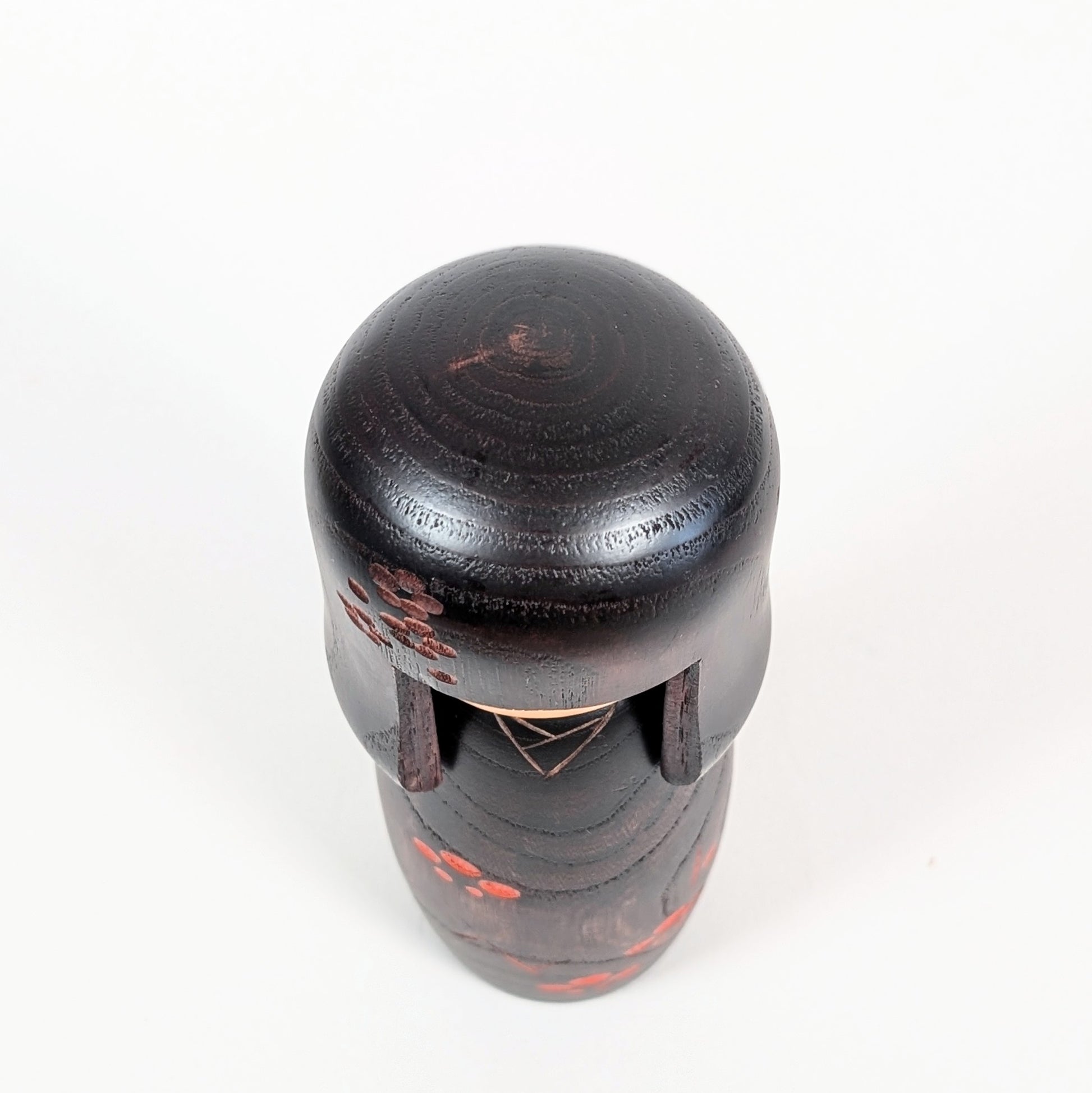 Vue du dessus d’une kokeshi Usaburo avec coiffure okappa en bois foncé