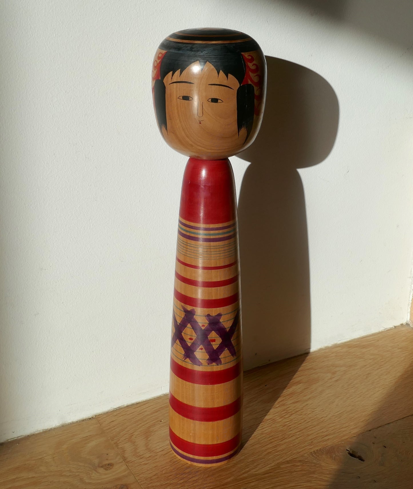 Poupée kokeshi japonaise ancienne Tsuchiyu photographiée en situation, artisanat vintage signé Abe Kazue.