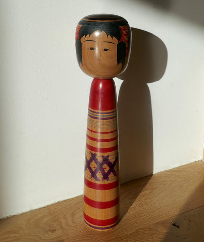 Poupée kokeshi japonaise ancienne Tsuchiyu photographiée en situation, artisanat vintage signé Abe Kazue.