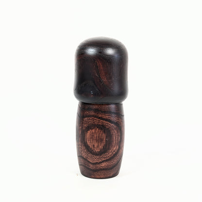 Dos d’une kokeshi vintage Usaburo Shunsai en bois foncé avec veinage apparent