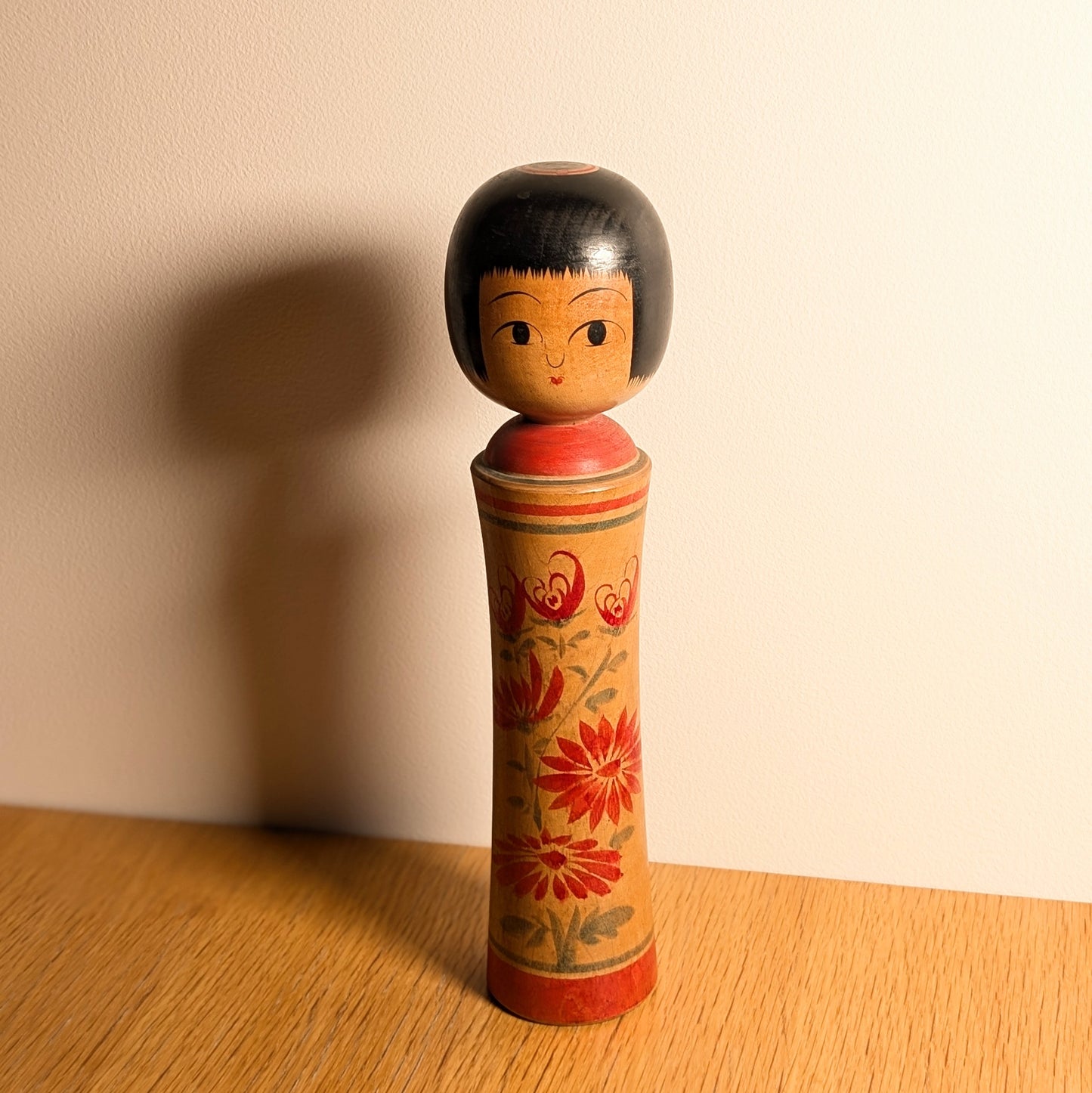 Kokeshi vintage Mamoru Izu en situation, objet de décoration japonaise authentique avec chrysanthèmes rouges