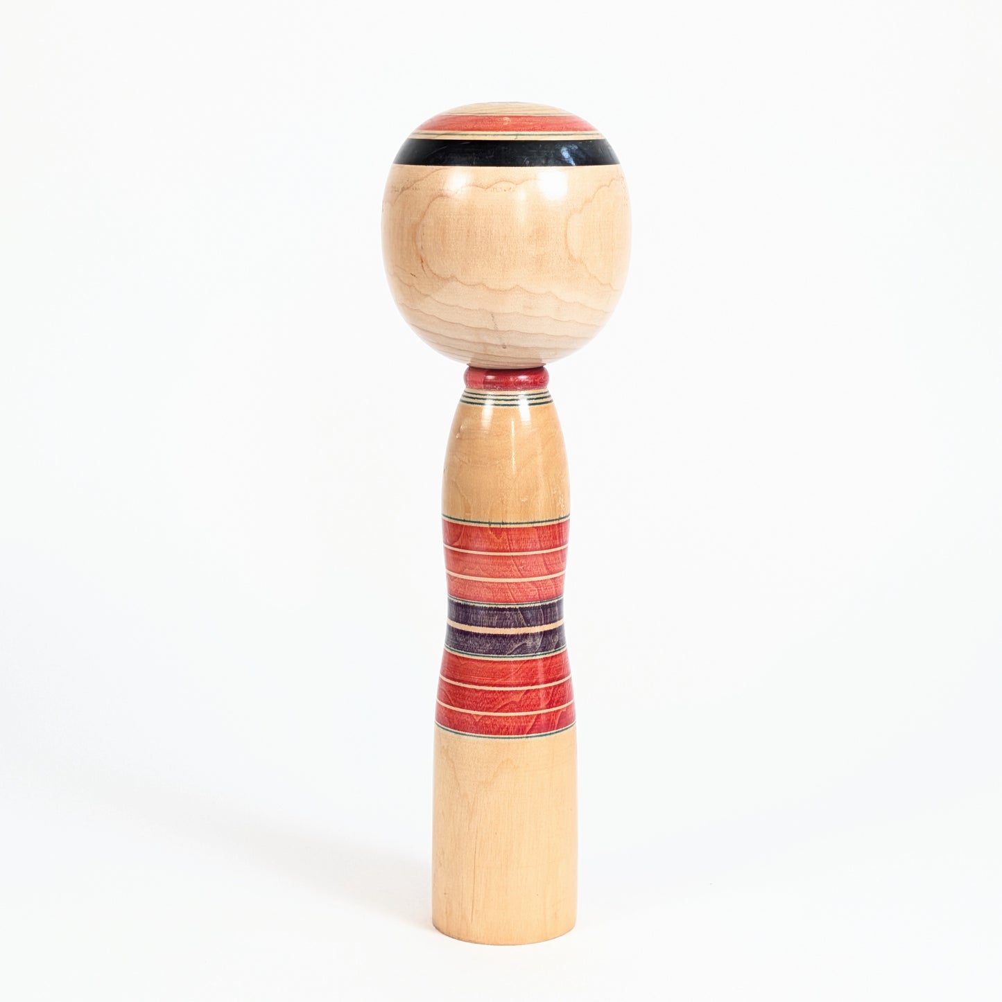 Dos d’une kokeshi vintage Yajiro avec bandes circulaires rokuro-moyo rouges et violettes sur bois naturel