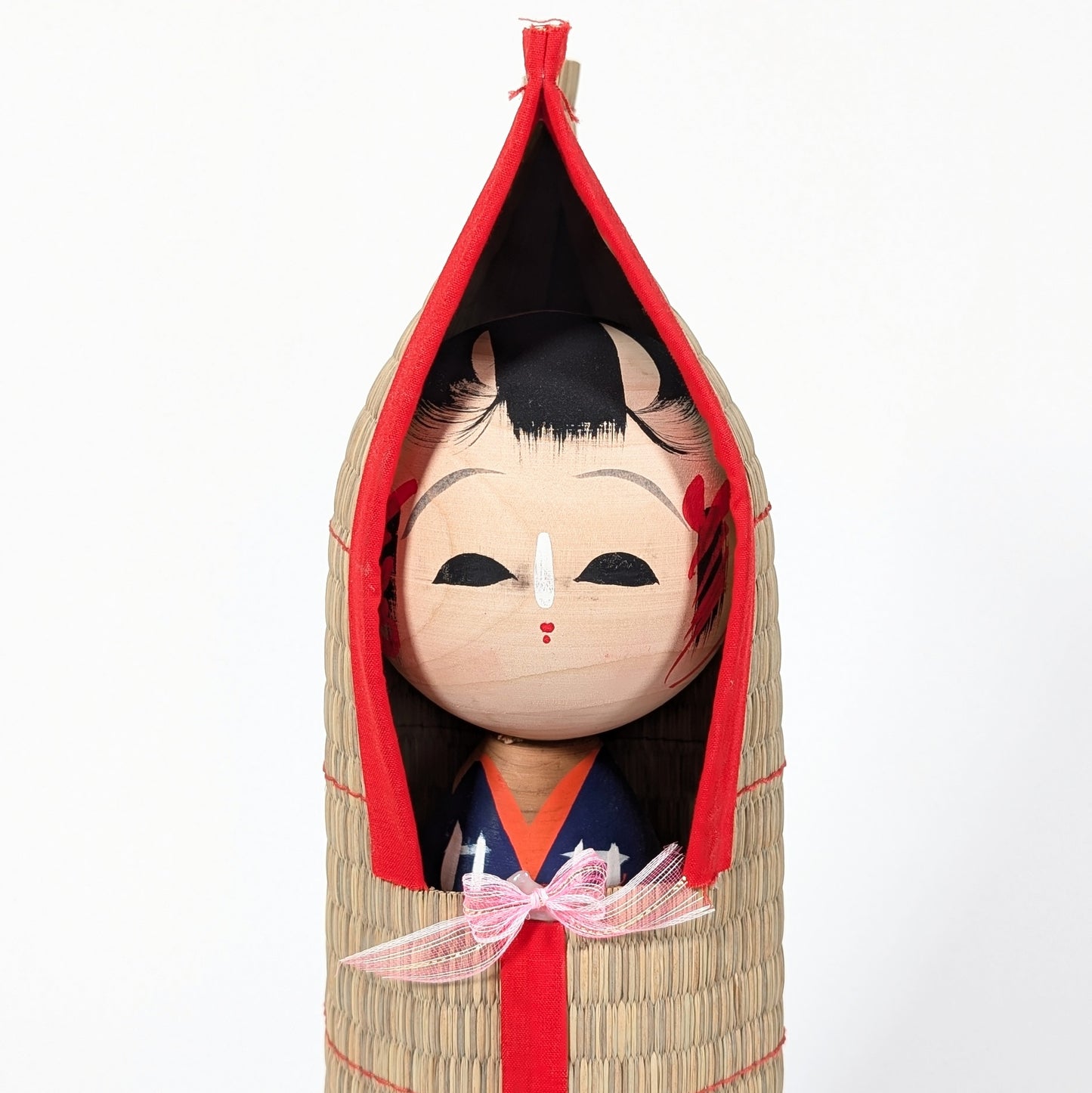 Détail du visage peint à la main d’une kokeshi japonaise, expression douce et artisanat traditionnel en bois