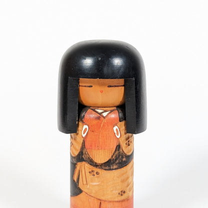 Détail du visage d’une kokeshi japonaise avec expression minimaliste et cheveux noirs laqués