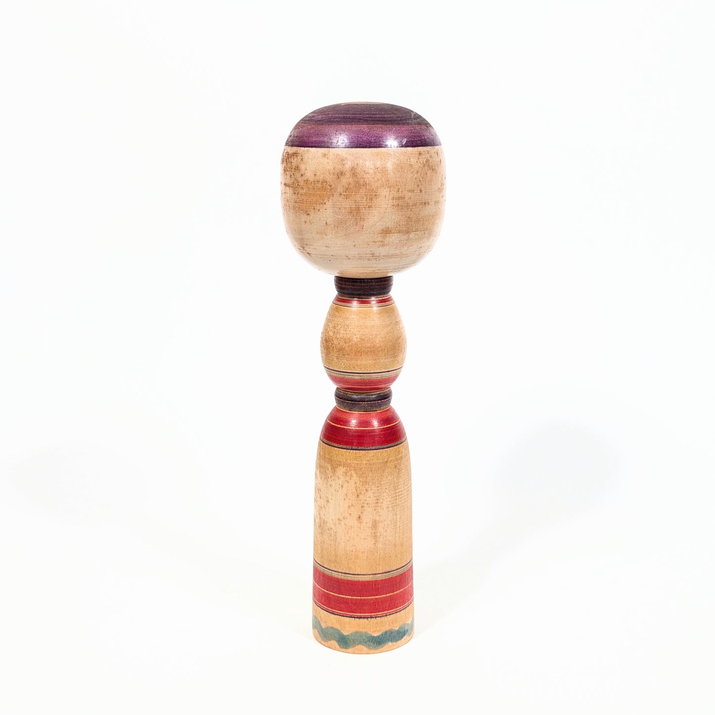 Dos d’une kokeshi Yajirō traditionnelle en bois tourné, avec lignes rouges et violettes réalisées au rokuro