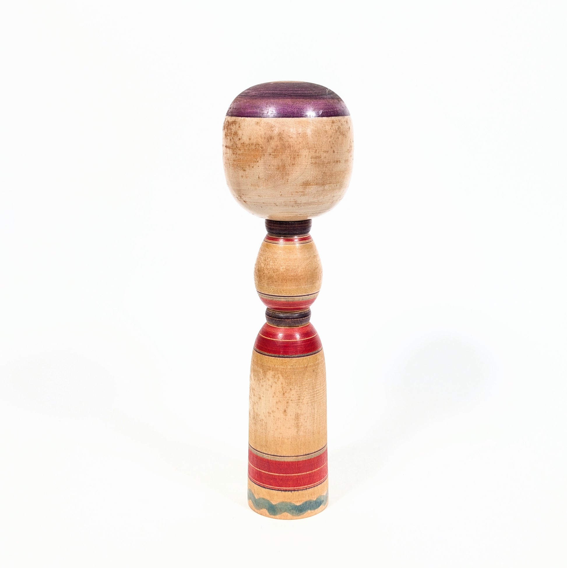 Dos d’une kokeshi Yajirō traditionnelle en bois tourné, avec lignes rouges et violettes réalisées au rokuro