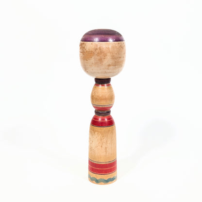Dos d’une kokeshi Yajirō traditionnelle en bois tourné, avec lignes rouges et violettes réalisées au rokuro
