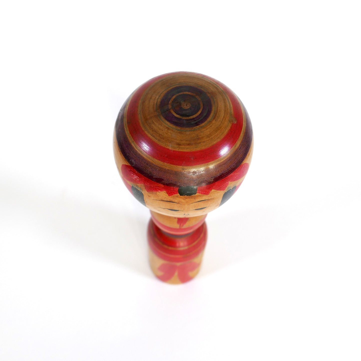 Vue du dessus d’une kokeshi Yajirō Niiyama Fukuo, coiffe circulaire à anneaux rouge et violet