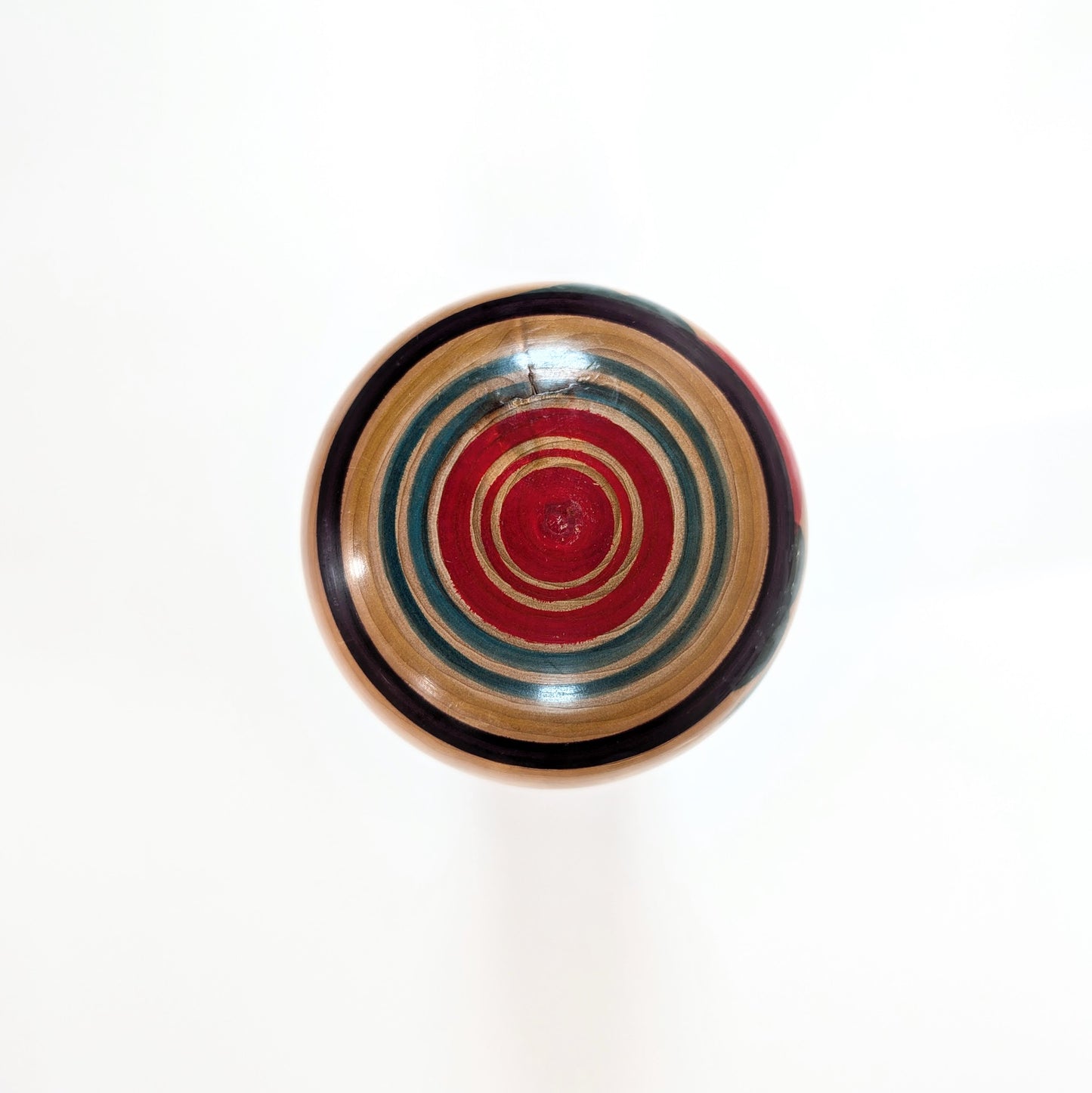 Vue du dessus de la tête de la Kokeshi Yajiro de Sato Naoki, avec motif Janome avec cercles peints rouges verts et violets typiques du style Yajiro.