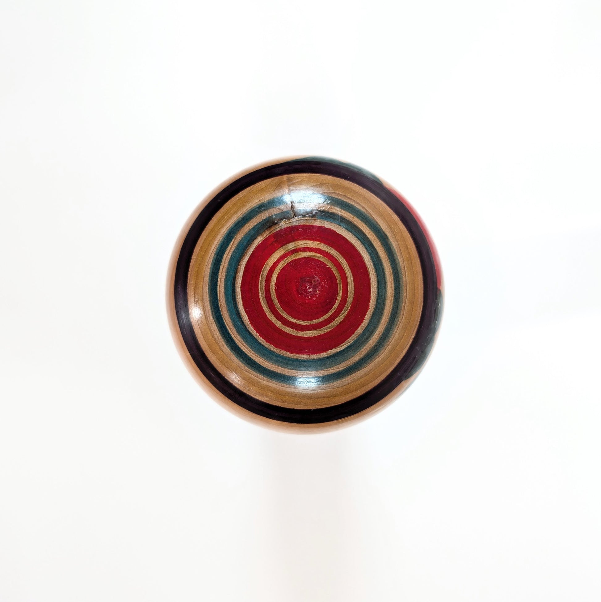 Vue du dessus de la tête de la Kokeshi Yajiro de Sato Naoki, avec motif Janome avec cercles peints rouges verts et violets typiques du style Yajiro.