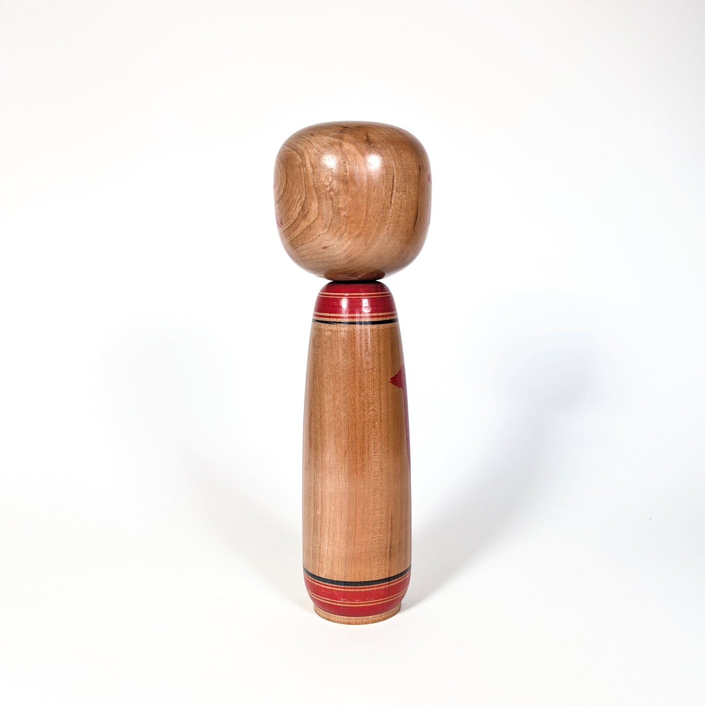 Vue de dos d’une kokeshi japonaise ancienne en bois naturel, école Yamagata, poupée japonaise artisanale période Showa
