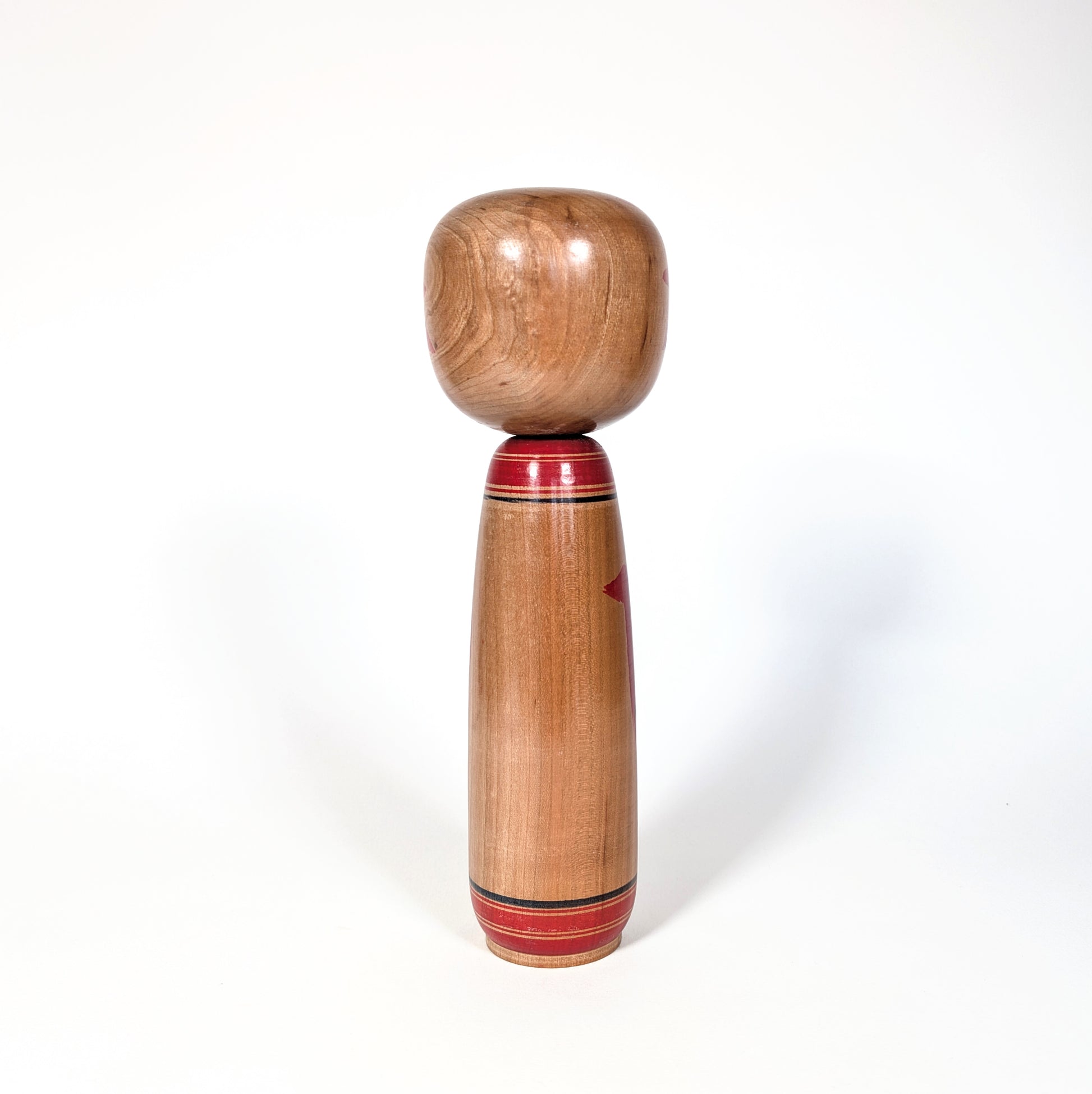 Vue de dos d’une kokeshi japonaise ancienne en bois naturel, école Yamagata, poupée japonaise artisanale période Showa
