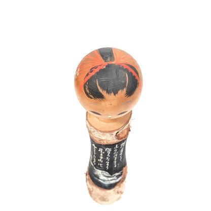 Vue du dessus d’une kokeshi Zao Onsen avec coiffure noire et ornements rouges peints à la main
