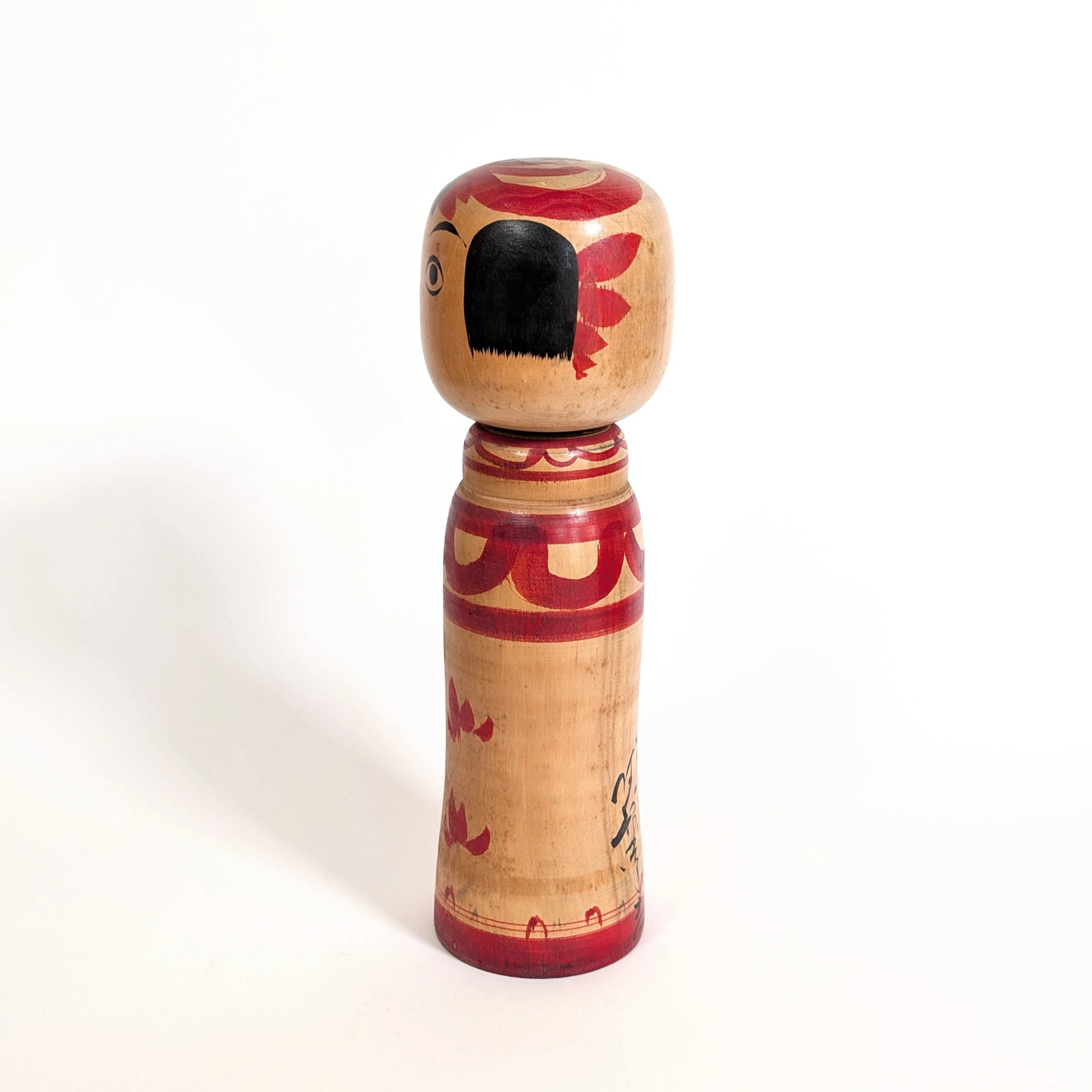 Profil d’une kokeshi Zao peinte à la main, décor aka-e rouge, artisanat japonais ancien en bois naturel