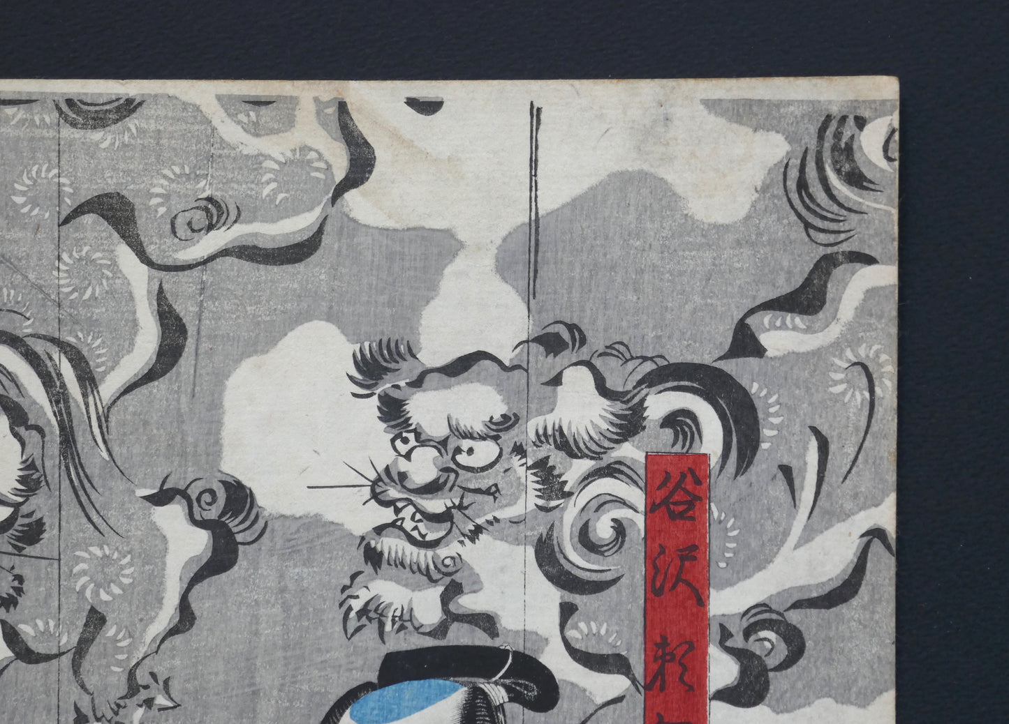 Coin supérieur droit de l’estampe de Kuniyoshi : cartouche rouge « Tanizawa Tanomo » avec lions gardiens (shishi) dans les nuées, ukiyo-e original, Edo 1849–1850 (Omegumi ni uruo Iwafuji).