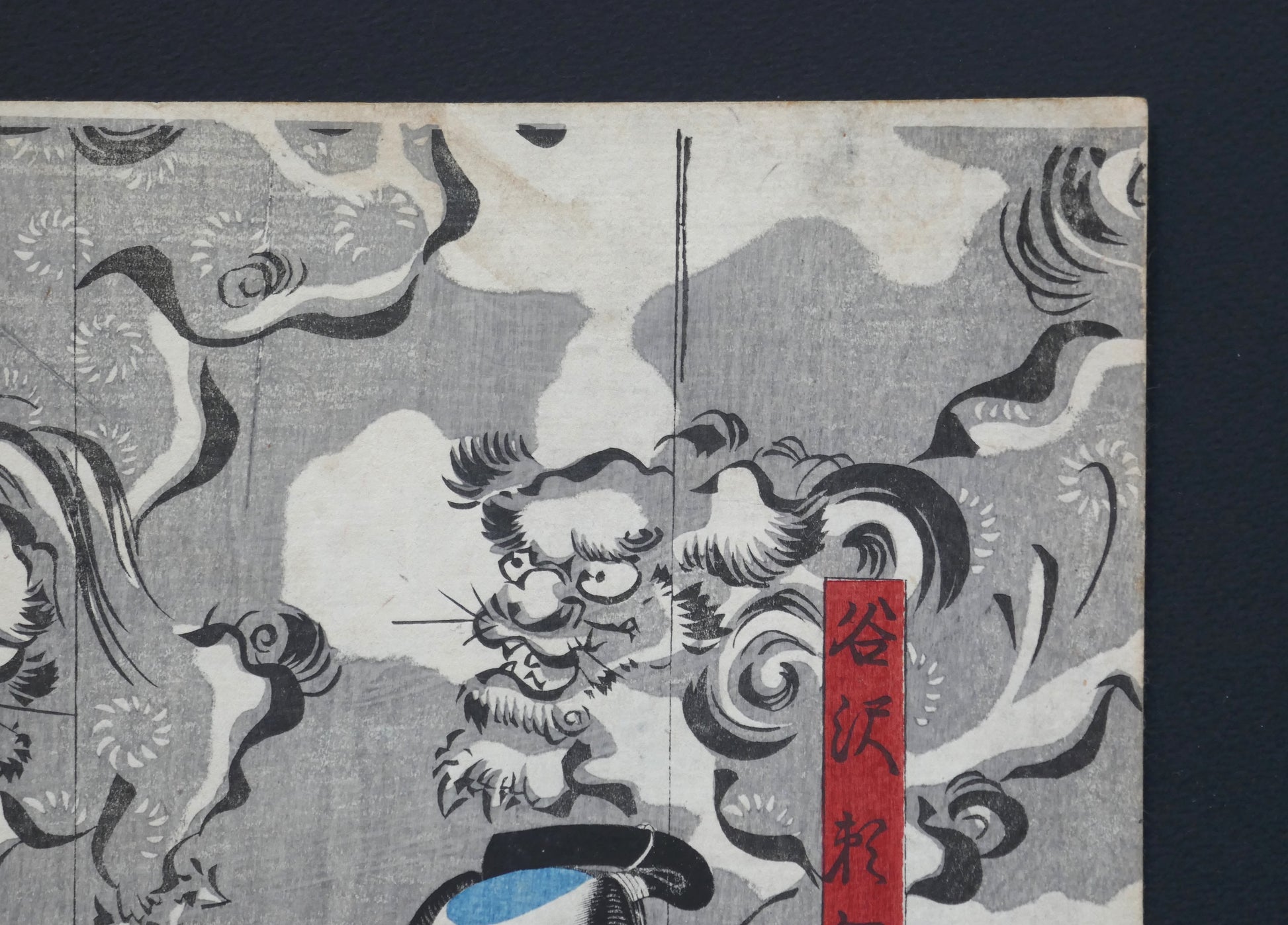 Coin supérieur droit de l’estampe de Kuniyoshi : cartouche rouge « Tanizawa Tanomo » avec lions gardiens (shishi) dans les nuées, ukiyo-e original, Edo 1849–1850 (Omegumi ni uruo Iwafuji).