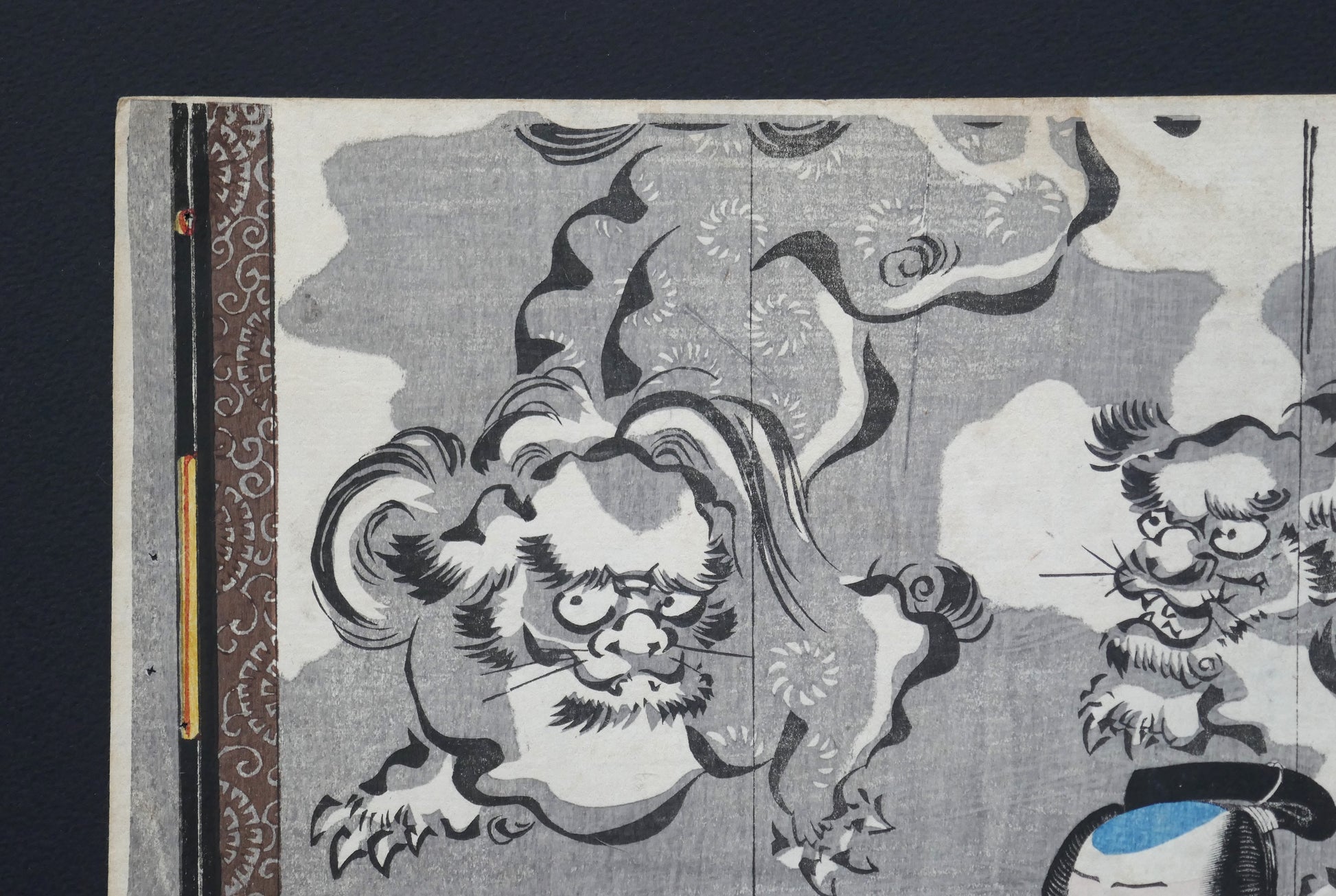 Coin supérieur gauche de l’estampe japonaise de Kuniyoshi : lions gardiens (shishi) sur fond de nuées devant un paravent, ukiyo-e gravure sur bois, Edo 1849–1850 (pièce kabuki Omegumi ni uruo Iwafuji).
