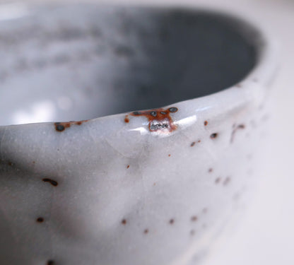 Gros plan de la lèvre du chawan Mino-yaki avec concentration ferrugineuse et variations naturelles de la glaçure Shino.
