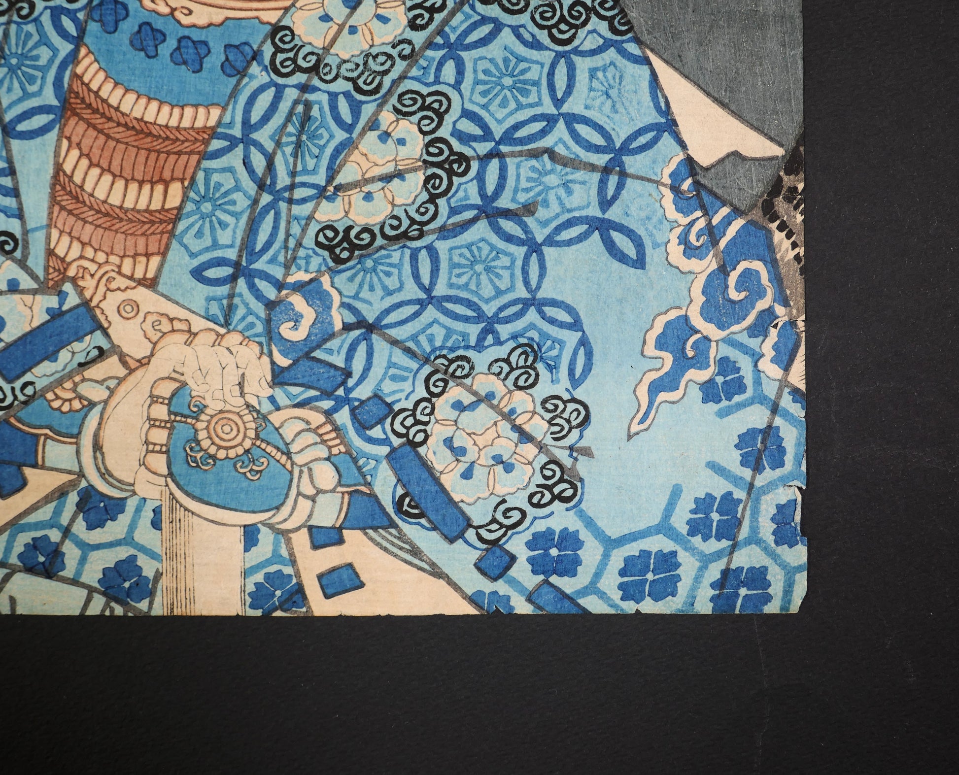 Détail de la manche bleue, des motifs japonais et du bord de papier ancien sur l’estampe Yoshitsune par Utagawa Kuniteru II.