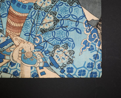 Détail de la manche bleue, des motifs japonais et du bord de papier ancien sur l’estampe Yoshitsune par Utagawa Kuniteru II.
