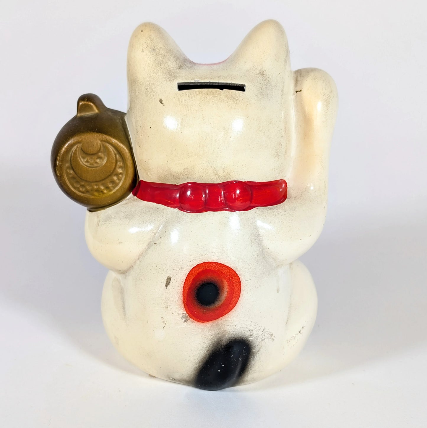 Dos d’un maneki-neko en céramique vintage, figurine traditionnelle japonaise servant de tirelire.