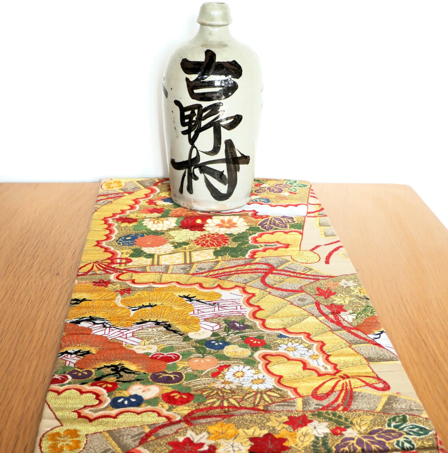 tokkuri décorative japonaise posée sur un maru obi sur une table en bois
