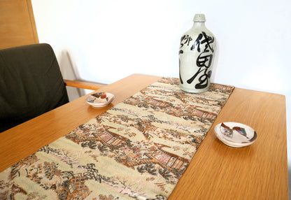 Maru obi vintage en soie, posé sur une table, décor de paysage japonais sur fond ivoire