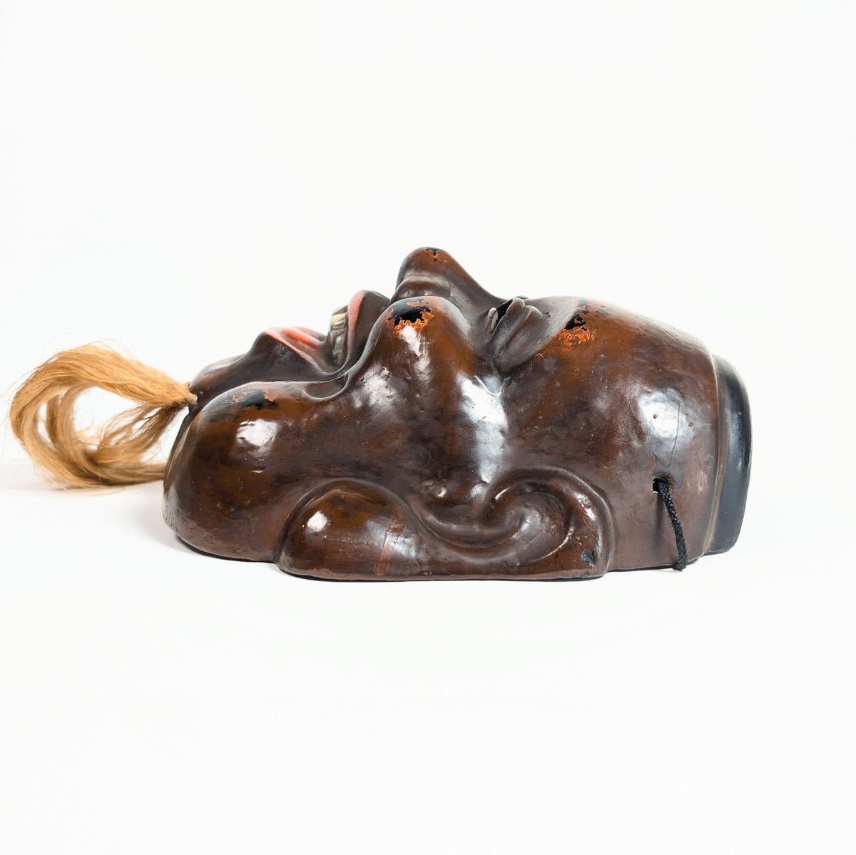 Profil d’un masque Daikoku en laque sèche japonaise, avec modelé profond des joues, des oreilles et du sourire.