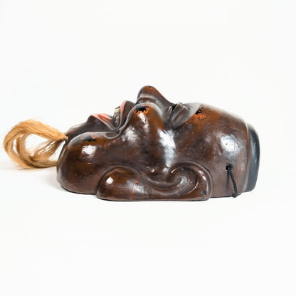 Profil d’un masque Daikoku en laque sèche japonaise, avec modelé profond des joues, des oreilles et du sourire.