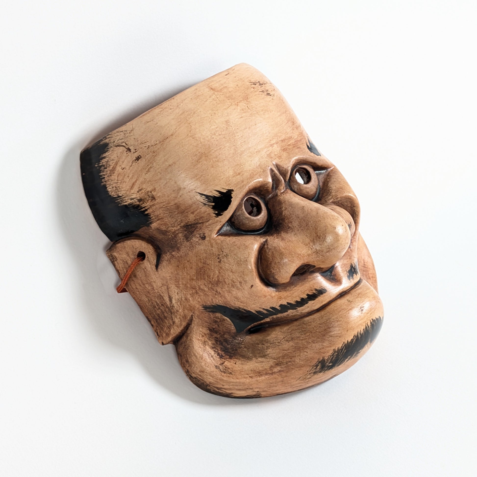 Vue de profil d’un masque démon japonais Beshimi en céramique, nez proéminent, bouche fermée et expression surnaturelle