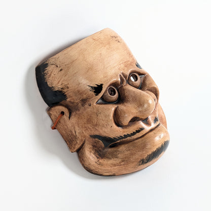 Vue de profil d’un masque démon japonais Beshimi en céramique, nez proéminent, bouche fermée et expression surnaturelle