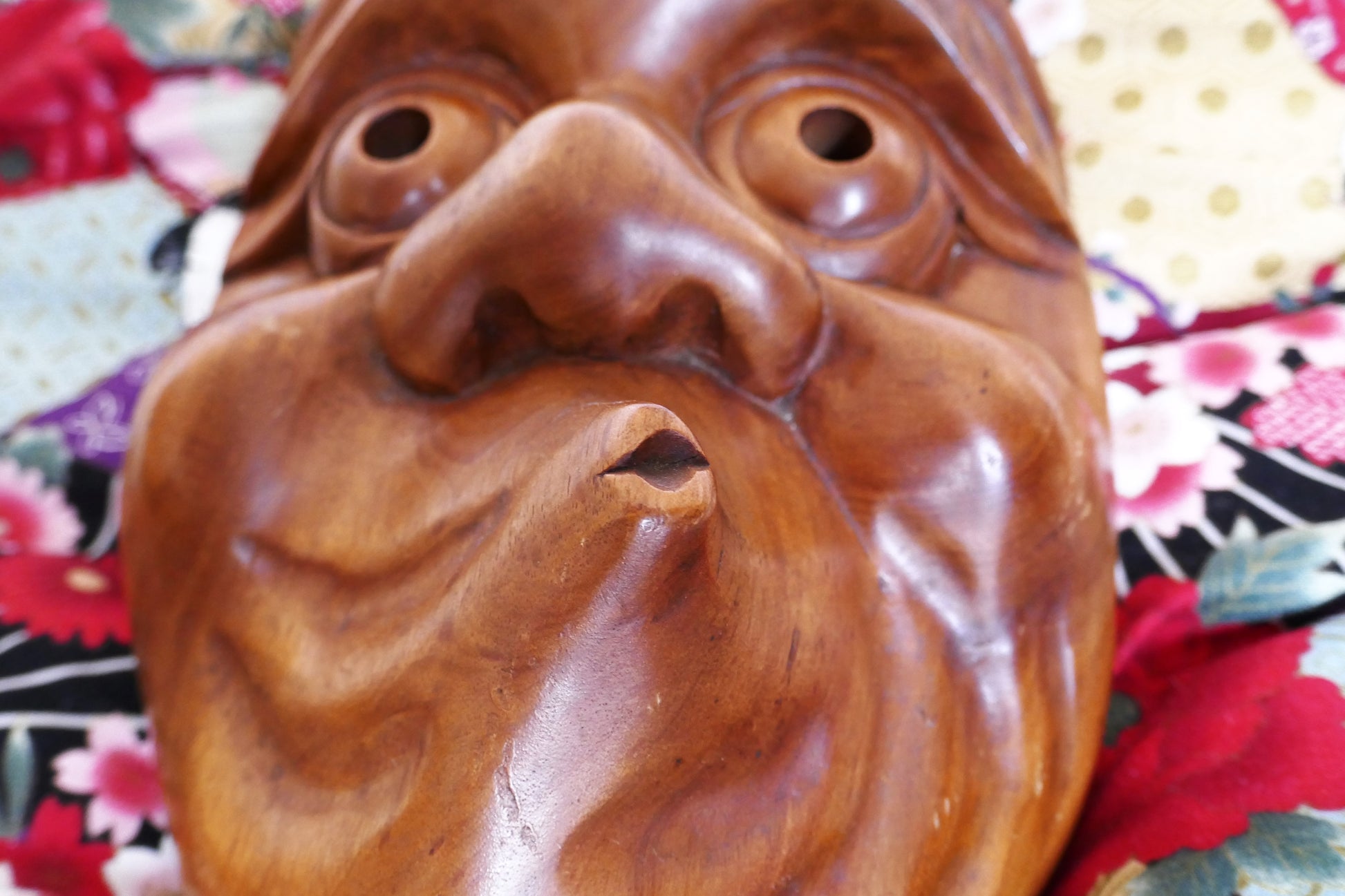 Gros plan sur la bouche tordue du masque Hyottoko, caractéristique du personnage comique soufflant du feu.