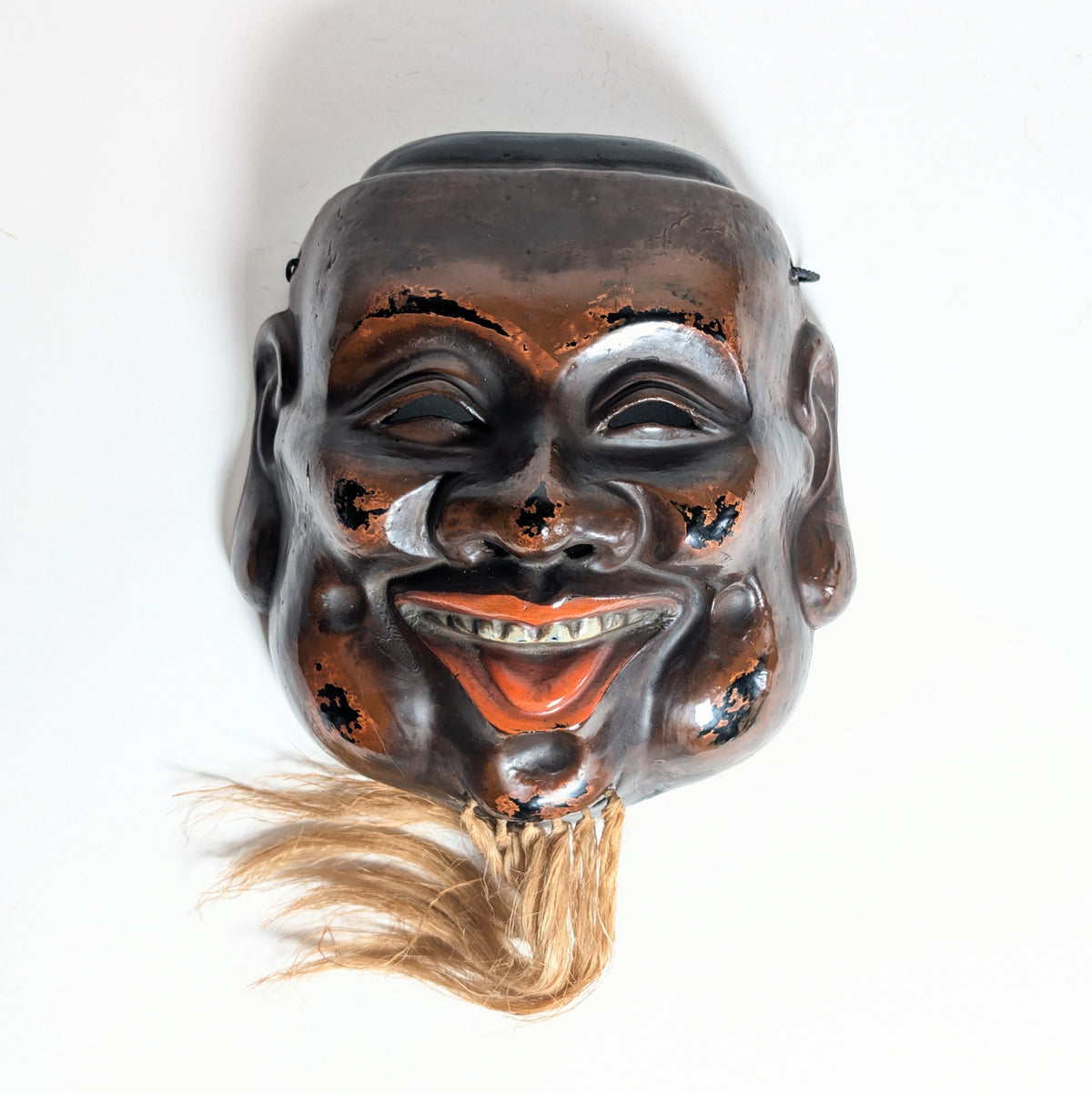 Masque japonais Daikoku vu de face, avec finition brun-rouge sur noir évoquant le Negoro et polychromie vermillon de la bouche.